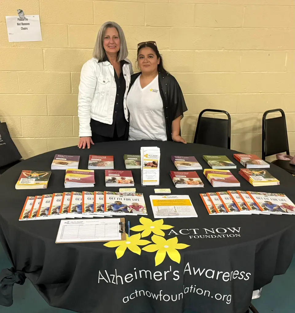 Staff members at a community event, offering free dementia resources and information at a table display.